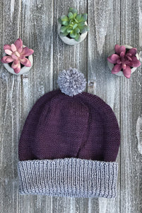 Knitted sample of toque in purple and grey. Shown with pompom